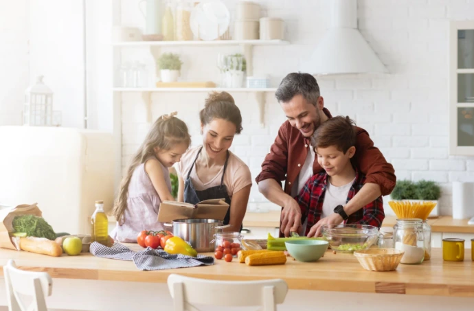 A family cooking together in the kitchen, preparing a meal and enjoying a warm, natural moment together.