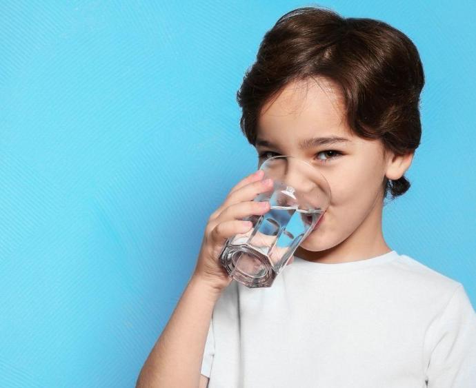 A smiling young boy in a white shirt drinks crystal-clear water from a glass, beside a bold badge reading “No. 1 in Ireland,” highlighting Renewell Water as Ireland’s leading water filter for clean, healthy hydration.